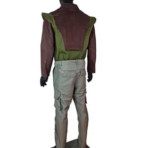 May include: A long-sleeved jacket featuring a dark brown upper section and a green lower panel with extended shoulder flaps, paired with light gray cargo pants. The outfit is displayed on a black mannequin against a plain white background.