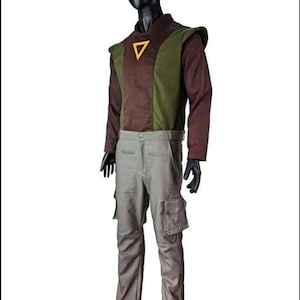 May include: A long-sleeved shirt featuring a brown and olive green color-blocked design with a yellow triangle emblem on the chest, paired with light gray cargo pants that include side pockets, displayed on a black mannequin against a white background.