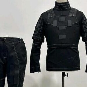 May include: A black tactical-style outfit consisting of a long-sleeved top with a high collar, shoulder padding, and rectangular chest patches, paired with matching trousers featuring reinforced leg panels and prominent white contrast stitching.