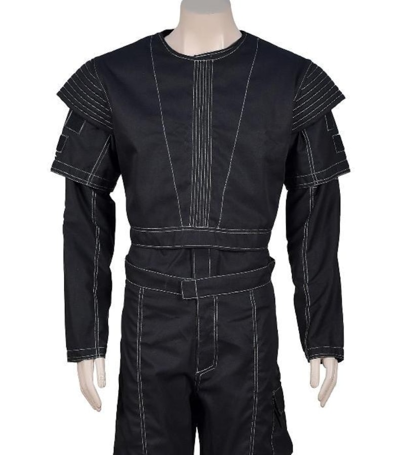 May include: Black jumpsuit with white stitching details. The long-sleeved top features a crew neck and structured shoulder accents. The waist is cinched with a belt, and the pants have pockets. The overall design is sleek and modern.