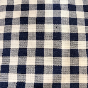 May include: A fabric featuring a classic gingham pattern with alternating dark navy blue and off-white squares. The textile displays a visible woven texture with a consistent grid design across the entire surface, creating a balanced checkerboard appearance.