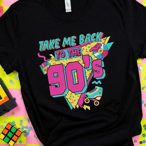 Może przedstawiać: Czarna koszulka z kolorową grafiką z napisem "TAKE ME BACK TO THE 90'S". Projekt zawiera boombox, rolki i inne elementy z lat 90. Widoczna jest również kaseta, kostka Rubika i lizak.