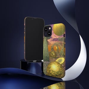 Op de afbeelding: Twee telefoonhoesjes. Eén is zwart, de andere heeft een kleurrijk surrealistisch landschapsontwerp met gele bollen, groene structuren en een paarse lucht. De telefoonhoesjes worden gepresenteerd op een donkerblauwe ondergrond met een reflecterende zwarte standaard.