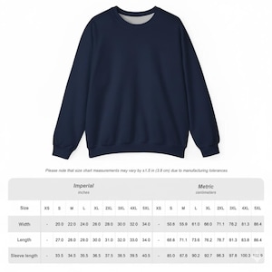 Puede incluir: Sudadera azul marino con cuello redondo. La imagen incluye una tabla de tallas con medidas en pulgadas y cent&iacute;metros. El texto de la tabla dice: "Tenga en cuenta que las medidas de la tabla de tallas pueden variar en &plusmn;1,5 pulgadas (3,8 cm) debido a las tolerancias de fabricaci&oacute;n."