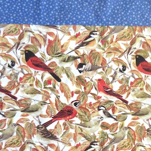 Puede incluir: Tela blanca con un borde estampado azul y un patrón repetido de pájaros rojos y marrones en ramas con hojas verdes.