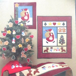 May include: A Christmas quilt pattern featuring a red, green, and white color scheme. The pattern includes a Christmas tree, Santa Claus, reindeer, and gingerbread men. The pattern is titled "It's Magic!" and includes Steam-A-Seam.