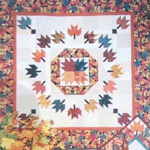 Peut inclure: Un bloc de courtepointe avec un motif central en étoile entouré d'un anneau de feuilles d'automne. Le bloc est encadré par une bordure de feuillage d'automne dans des tons de rouge, orange, jaune et vert.