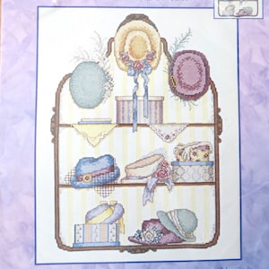 Puede incluir: Un patrón de punto de cruz contado para una colección de sombreros. El patrón presenta un estante con varios sombreros, cajas y cintas. El patrón mide 27,9 cm x 35,6 cm (11 pulgadas x 14 pulgadas) y fue diseñado por Jane Chandler.