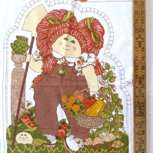 Puede incluir: Un patr&oacute;n de tela con una ni&ntilde;a de pelo rojo que lleva un mono y sostiene una cesta de verduras. La ni&ntilde;a est&aacute; de pie en un jard&iacute;n con una rana, flores y setas. El patr&oacute;n incluye instrucciones para hacer una mu&ntilde;eca Cabbage Patch Kid. El texto del patr&oacute;n dice "Cabbage Patch Kids" y "Dejar abierto para rellenar".