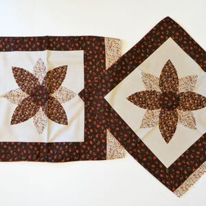 Peut inclure: Deux housses de coussin à motifs floraux marrons et blancs avec une bordure marron et un centre blanc orné d'un motif floral marron et blanc.