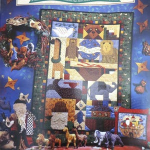May include: A colorful display featuring a quilt with animal designs, a wreath, and various ornaments. The quilt showcases a dove, raccoon, giraffe, lion, and elephant. The text "NOAH'S NOEL" and "PEACE ON EARTH" are visible. The display includes a Santa Claus figure and other decorative elements.