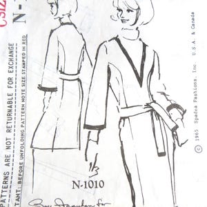 May include: Vintage Spadea Designer Pattern N-1010 featuring a shift dress design. The illustration shows a long-sleeved dress with a V-neck and a belt. The pattern includes text and a signature.