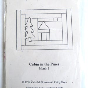 Puede incluir: Dibujo en blanco y negro de una cabaña con un árbol delante. El texto "Folk Art Christmas Block of the Month" está en la parte superior de la imagen. El texto "Cabin in the Pines Month 1" está debajo del dibujo. El texto "©1996 Vicki McGowen and Kathy Hock Distributed by Quakertown Quilts Phone (281)996-1756" está en la parte inferior de la imagen.