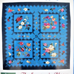 May include: Color Palette Applique quilt pattern featuring four floral designs, each in a different color palette. The title "The Seasons in Bloom" and the designer's name "Sheila Wintl" are printed below the quilt design. A bonus technique booklet is included.