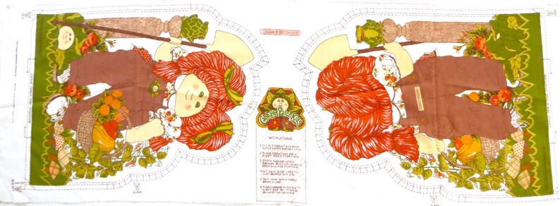 Puede incluir: Un panel de tela con dos im&aacute;genes de una ni&ntilde;a pelirroja con un mono y sosteniendo una pala. La ni&ntilde;a est&aacute; rodeada de follaje verde y flores. El panel incluye el texto "Country Girl Charm" e instrucciones para hacer una mu&ntilde;eca.