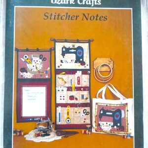 May include: A set of three wall hangings featuring a sewing theme. The hangings are made of fabric and feature a sewing machine, needles, thread, and other sewing supplies. The hangings are decorated with a red, white, and blue color scheme. The text "Doily Decor by Ozark Crafts" and "Stitcher Notes" is visible on the image.