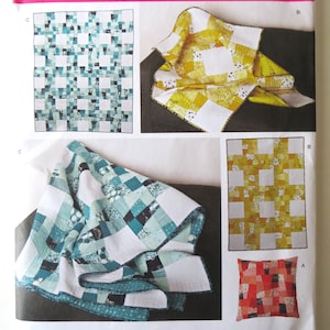 May include: Simplicity sewing pattern 1390 OS features quilt designs. The pattern includes instructions for various quilt sizes and a pillow. The quilts showcase patchwork designs in shades of blue, yellow, and red. The pattern is designed and printed in the USA.