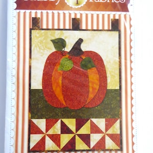 May include: A package for a fabric craft project featuring a pumpkin design. The package has a vertical striped background with a pumpkin applique in the center. The text "Shabby Fabrics" and "Little Blessings - Pumpkin Patch" are visible.