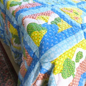 May include: A blue, green, yellow, and white patchwork quilt with a quilted design. The quilt is made of different fabrics with floral patterns.