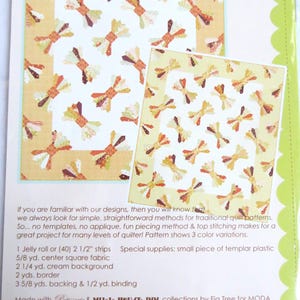 May include: Quilt pattern for a "Bow Tie" quilt with a cream background and colorful bow tie designs. The pattern is 59 1/2 inches by 68 inches and includes instructions for making the quilt. The pattern is made with "Patisserie" and "Mill House Inn" collections by Fig Tree for Moda.