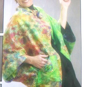 May include: A poncho featuring a vibrant, multi-colored sunflower pattern in shades of green, yellow, orange, and purple. The garment includes a solid green patch pocket on the front and a dark green base layer underneath. The text FAST FASHION! is visible.