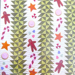 Peut inclure: Une courtepointe blanche avec un motif géométrique vert et brun. La courtepointe est décorée d'hommes en pain d'épices, de cannes en sucre, d'étoiles et de biscuits.