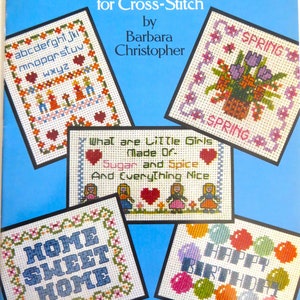 May include: A book cover with the title "Quick-and-Easy Miniature Samplers for Cross-Stitch" by Barbara Christopher. The cover features five colorful cross-stitch designs, including an alphabet sampler, a spring floral sampler, a sampler with the text "What are Little Girls Made Of Sugar and Spice And Everything Nice", a sampler with the text "Home Sweet Home", and a sampler with the text "Happy Birthday".