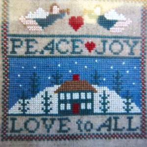May include: Cross-stitch sampler with a winter scene featuring a house, trees, and falling snow. The text reads "Peace Joy Love to All".