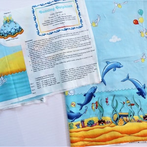 May include: A sewing pattern for a girl's jumper featuring a dancing dolphin design. The pattern includes instructions and measurements for sizes 2, 4, 6, or 8. The fabric is blue with white clouds and yellow accents. The pattern is titled "Dancing Dolphins".