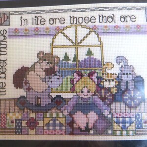 Puede incluir: Patrón de punto de cruz con una colcha de retazos colorida con una ventana y varios animales de peluche. El texto dice "En la vida son aquellos que se sienten en el corazón, las mejores cosas".