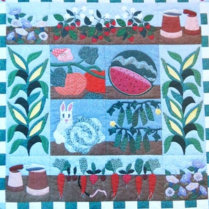 以下が含まれることがあります： 庭をテーマにしたキルト。イチゴ、トマト、スイカのスライス、ニンジン、ウサギなどの刺繍が施されています。キルトは青と白のチェック柄のボーダーで、cm単位で測定されています。