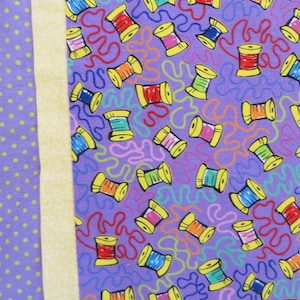 Puede incluir: Tela morada con un patrón de lunares blancos, tela amarilla con un patrón blanco y tela morada con un patrón de carretes de hilo coloridos.
