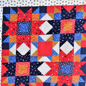 May include: A patchwork quilt with a red, white, and blue color scheme. The quilt is made up of squares and triangles, and features a variety of floral and geometric patterns.