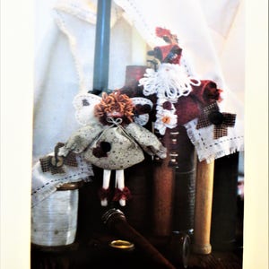 May include: A vintage craft pattern for a Christmas table runner and ornaments. The pattern is titled "#123 LIT'L BIT OF CHRISTMAS (Ornaments & Table runner)". The image shows a close-up of the pattern with a handmade doll and Santa ornament.