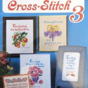 May include: A book cover with the title "Christian Cross-Stitch 3". The cover features five framed cross-stitch designs with various Christian themes, including flowers, fruit, and inspirational quotes. The designs are in a white and red color scheme.