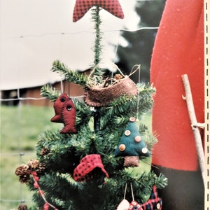 May include: A small artificial Christmas tree decorated with handmade ornaments. The ornaments include a red and black plaid star, a brown felt bird's nest, a green felt Christmas tree, and two red and white plaid fish ornaments.