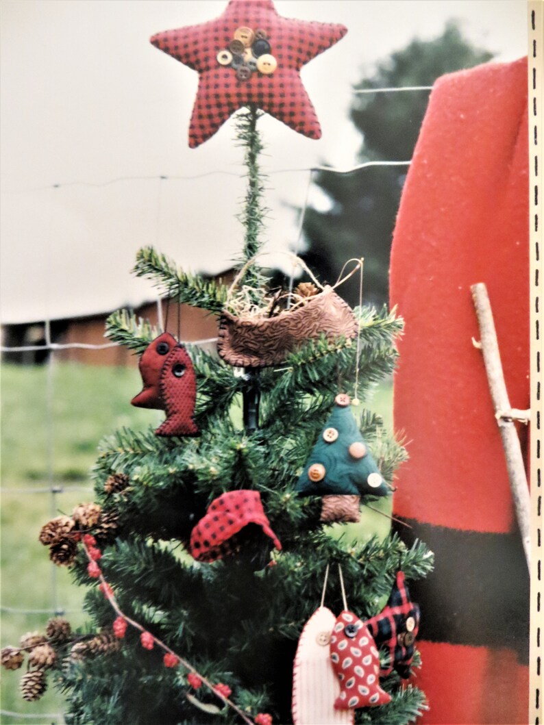 May include: A small artificial Christmas tree decorated with handmade ornaments. The ornaments include a red and black plaid star, a brown felt bird's nest, a green felt Christmas tree, and two red and white plaid fish ornaments.