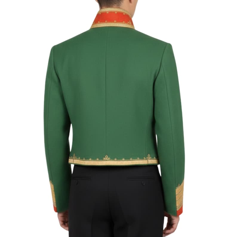 K&ouml;nnte beinhalten: Gr&uuml;ne Jacke mit goldfarbenen Verzierungen und roten Akzenten an Kragen und Manschetten. Die Jacke hat eine taillierte Passform und wird mit einer schwarzen Hose getragen. Das Design der Jacke weist verzierte goldene Stickereien an den Kanten auf.