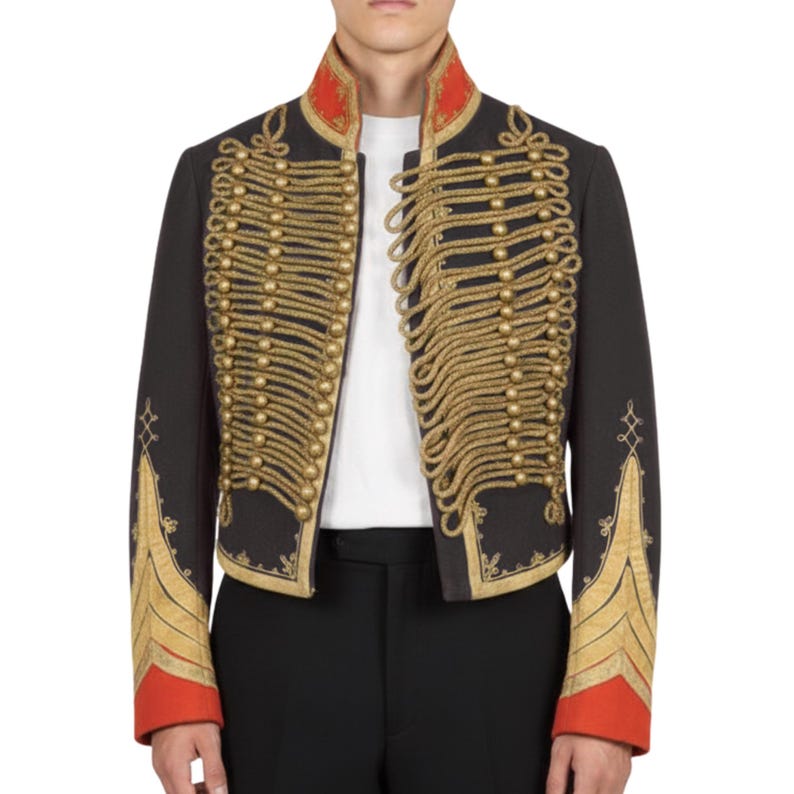 K&ouml;nnte beinhalten: Schwarze Jacke im Milit&auml;rstil mit goldenen Seildetails und goldenen Kn&ouml;pfen. Die Jacke hat einen roten Kragen und Manschetten mit goldener Stickerei auf den &Auml;rmeln. Ein wei&szlig;es Hemd ist darunter sichtbar.