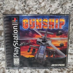 May include: A PlayStation game case for "Gunship" featuring a helicopter graphic against a sunset backdrop. The case has the PlayStation logo and the Micro Prose logo. The game is rated "Kids to Adults".