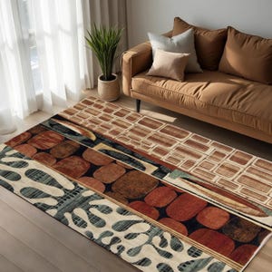 Op de afbeelding: Een rechthoekig vloerkleed met een geometrisch patroon in bruin-, beige- en blauwtinten. Het kleed heeft verschillende vormen, waaronder rechthoeken, ovalen en organische vormen. Het ligt op een houten vloer, in de buurt van een bruine bank.