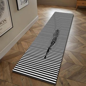 Könnte beinhalten: Ein schwarz-weiß gestreifter Läuferteppich mit einem 3D-Zebra-Design. Der Teppich hat ein sich wiederholendes Muster aus schwarzen und weißen horizontalen Streifen, das eine optische Täuschung erzeugt. Das Zebra-Design scheint aus der Oberfläche des Teppichs herauszutreten.