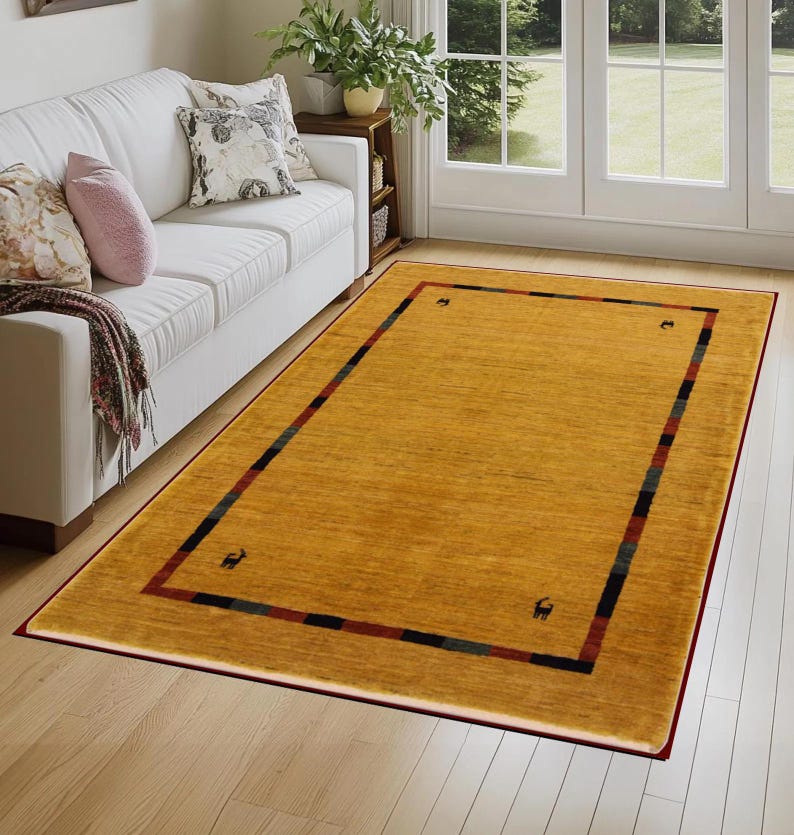 May include: Mustard yellow rectangular area rug with a dark red border. The rug has a striped design in the border with black, green, and red stripes. Small animal silhouettes are in each corner. The rug is placed on a hardwood floor.