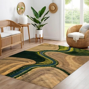 May include: Area rug with a landscape design featuring a winding road through fields of brown and green. The rug has a rectangular shape and is placed on a wooden floor. The rug's design resembles an aerial view of a natural landscape.