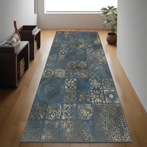 May include: A long, rectangular rug with a patchwork design. The rug features a dark blue background with gold-coloured geometric and floral patterns. The rug is placed on a wooden floor in a hallway.