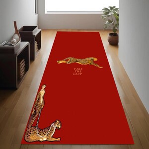 May include: A red runner rug featuring a cheetah design. The rug has two cheetah illustrations, one leaping and one resting. The text "TAKE THE LEAP" is printed on the rug.