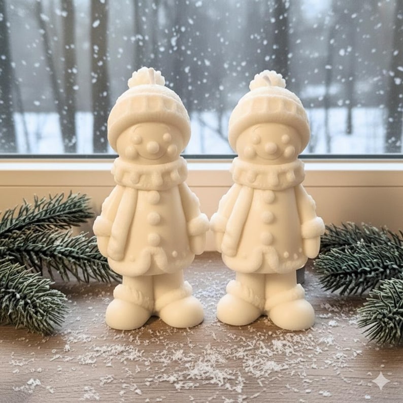 May include: Two off-white snowman figurines. Each snowman wears a hat with a pom-pom, a scarf, and a coat with buttons. The snowmen are standing on a wooden surface with faux snow and pine needles.