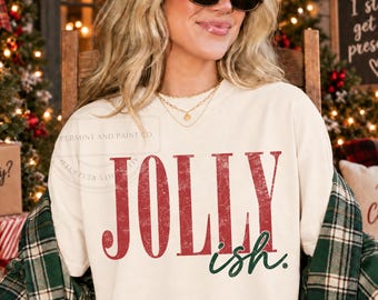 Op de afbeelding: Een crèmekleurig sweatshirt met ronde hals voorzien van het woord JOLLY in grote, verweerde rode hoofdletters, met het woord ish in een kleiner, donkergroen cursief lettertype onder de hoofdtekst op de voorzijde.