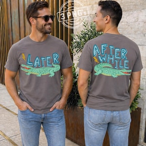 May include: Two people wearing gray t-shirts with alligator graphics. One shirt says "LATER" with a green alligator and a yellow lightning bolt. The other shirt says "AFTER WHILE" with a green alligator and a yellow lightning bolt.
