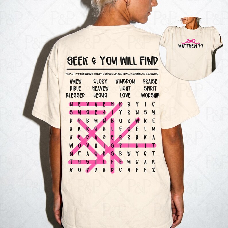 May include: A cream-colored t-shirt featuring a word search puzzle on the back with the text SEEK & YOU WILL FIND and a list of faith-based words. Several words are highlighted with pink lines. The front chest area displays a small pink bow and the text MATTHEW 7:7.